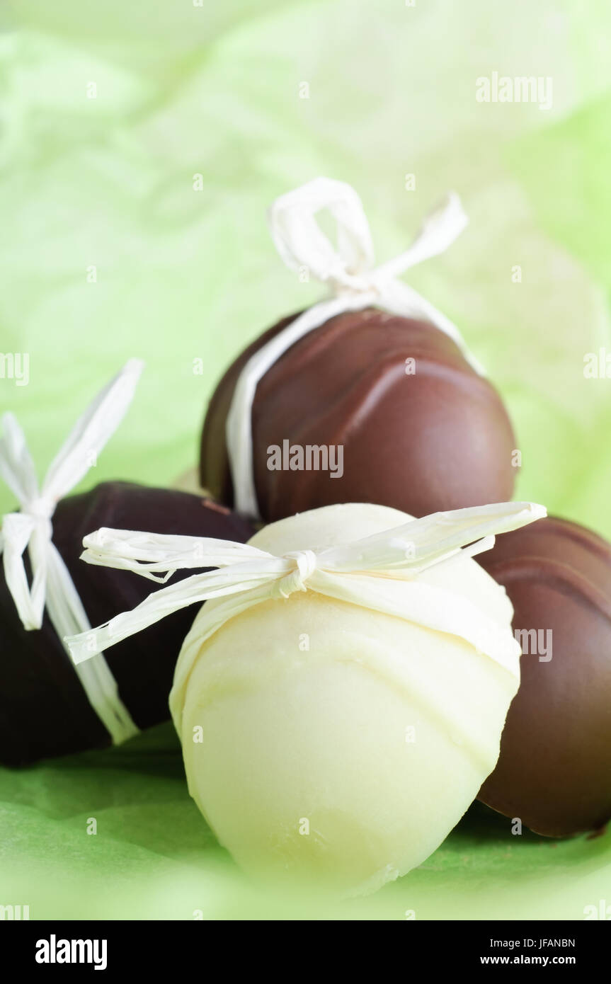 Un gruppo di fatto in casa a forma di uovo di pasqua cioccolatini, prua legate con nastro di rafia su una fresca e leggera molla sfondo verde. Foto Stock