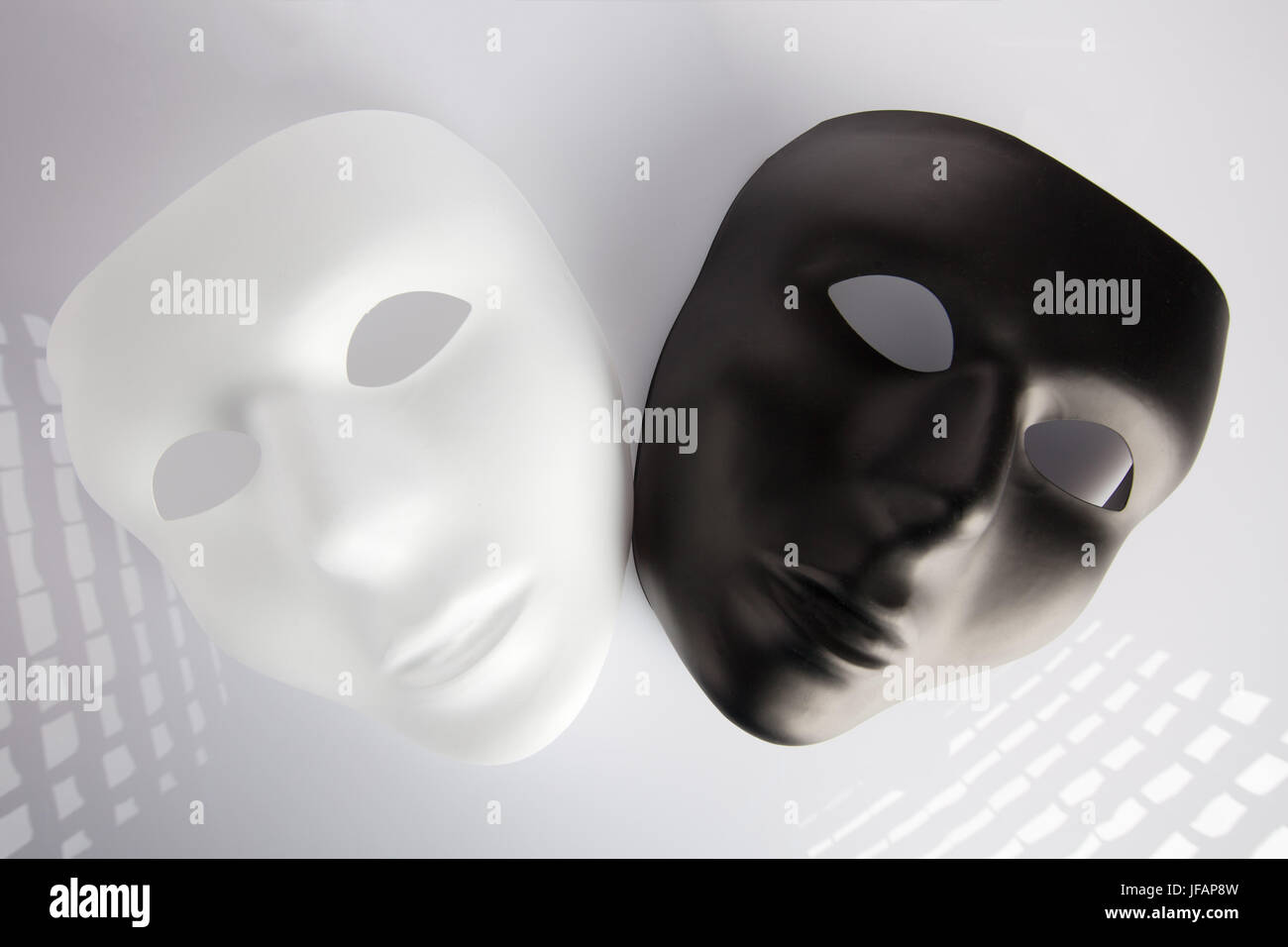 In bianco e nero le maschere su superficie bianca Foto Stock