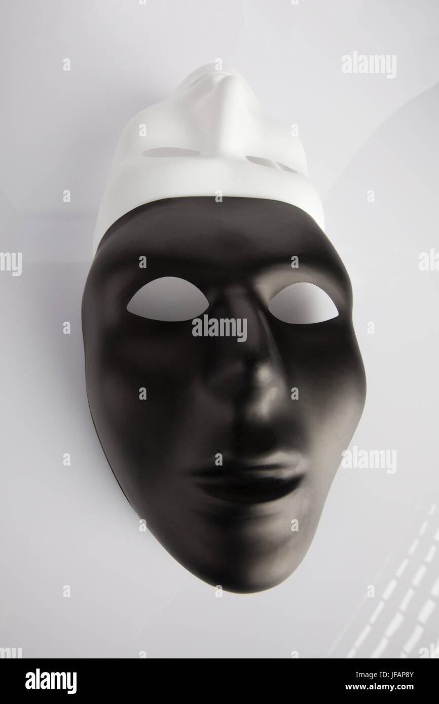 Bianco e nero maschere unita su bianco sfondo riflettente. Grandangolo, l'immagine verticale, vista dall'alto. Foto Stock