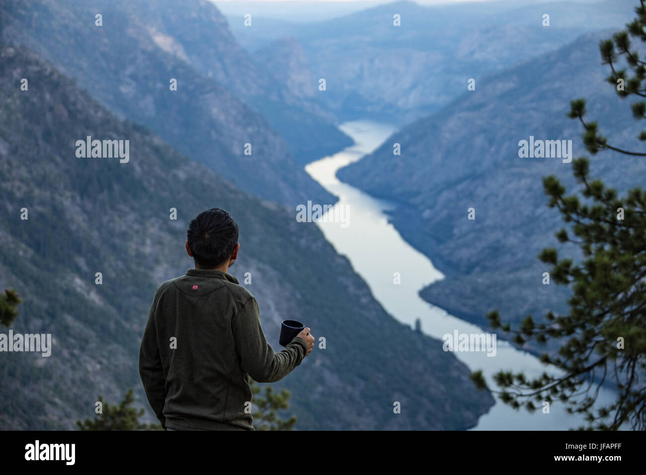 Escursionista di bere il caffè mentre guardando verso il basso sulla Hetch Hetchy, Yosemitie Pakr nazionale, CALIFORNIA, STATI UNITI D'AMERICA Foto Stock