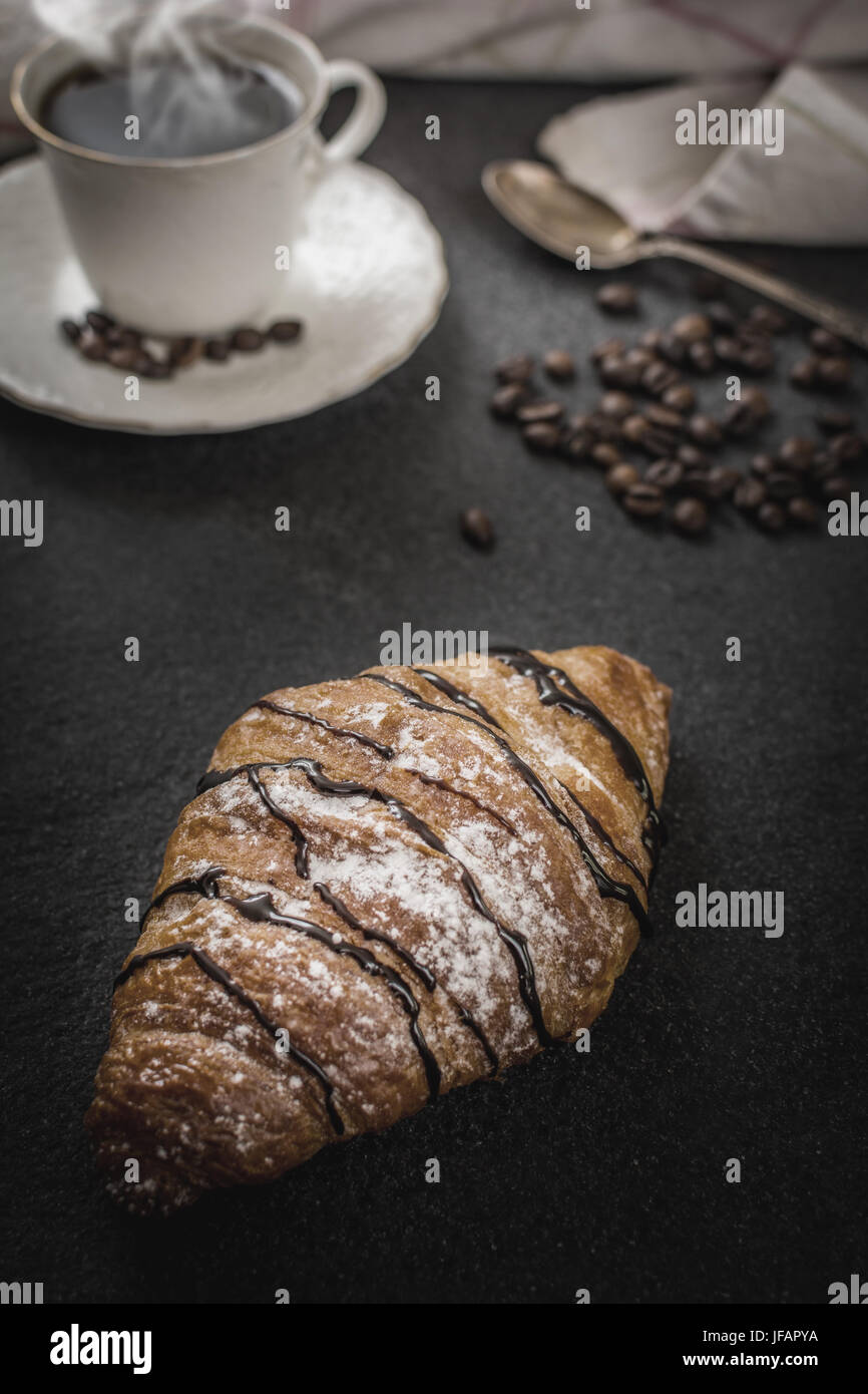 Francese tradizionale prima colazione con croissant al cioccolato e caffè nero sul tavolo di pietra Foto Stock