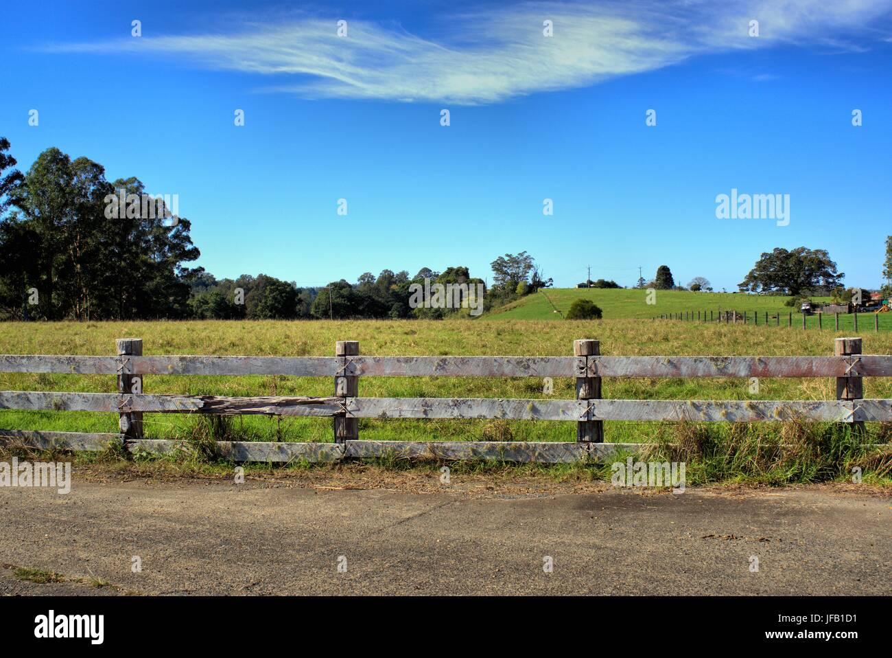 La bellissima campagna scenario di erba recintato paesaggio con cielo azzurro e gli alberi in lontananza nel Nuovo Galles del Sud, Australia Foto Stock