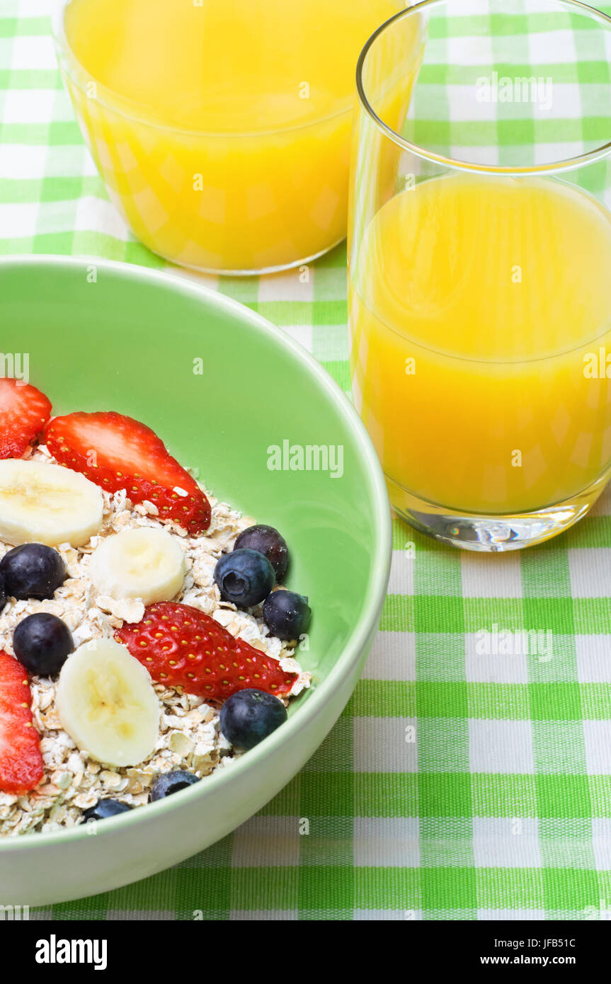 Una sala colazione con una ciotola di frutta fresca e avena muesli e succhi di arancia su una verde e bianco tovaglia gingham. Foto Stock