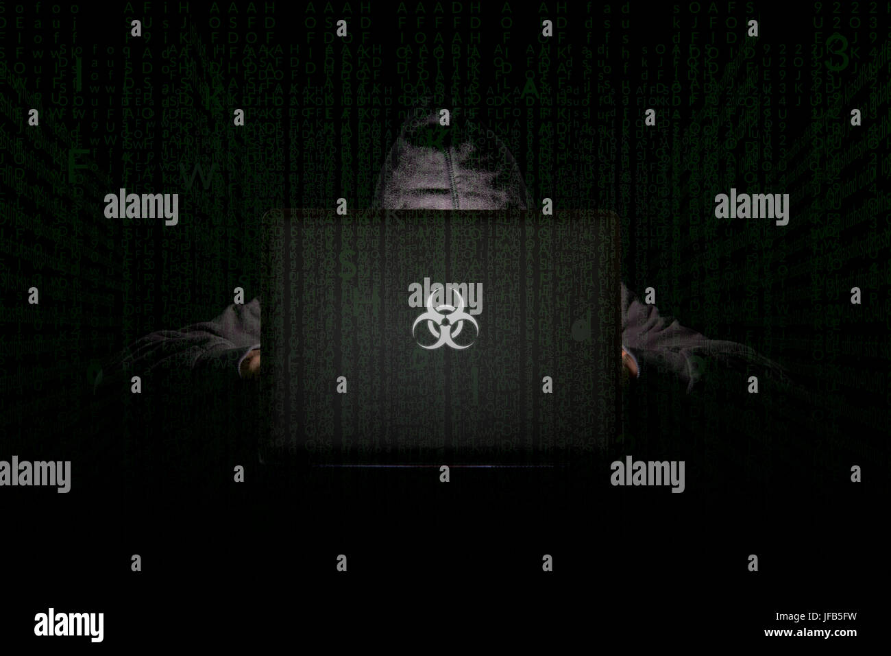 Una persona in una stanza buia che utilizza un laptop con un logo di rischio biologico, phishing su Internet, hacking, minacce alla sicurezza dei dati, violazione dei dati, concetto di sicurezza informatica Foto Stock