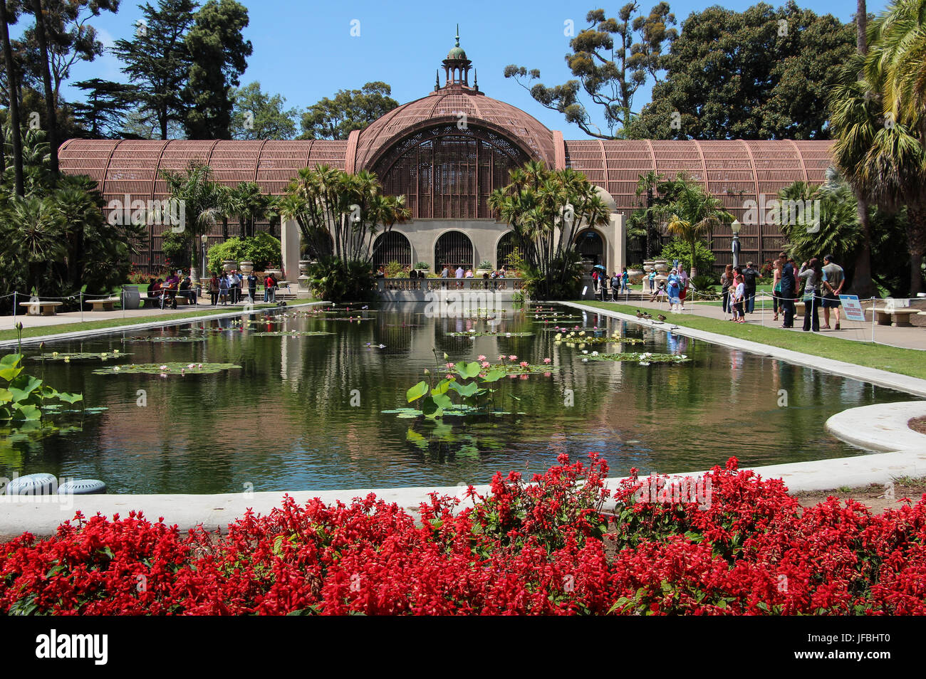 Uno dei più grandi del mondo di assicella di strutture integrate, l'edificio botanico in Balboa Park, San Diego, vista lungo il laghetto di gigli, fiori di colore rosso, blu cielo Foto Stock