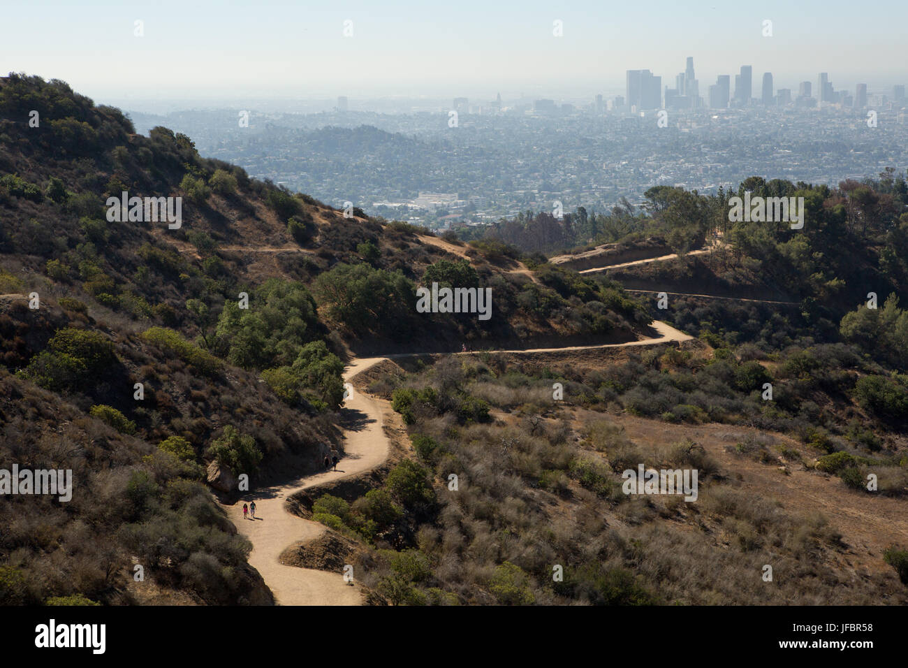 Gli escursionisti seguire un percorso di avvolgimento nelle Colline di Hollywood. Inquinamento atmosferico pende su Los Angeles. Foto Stock