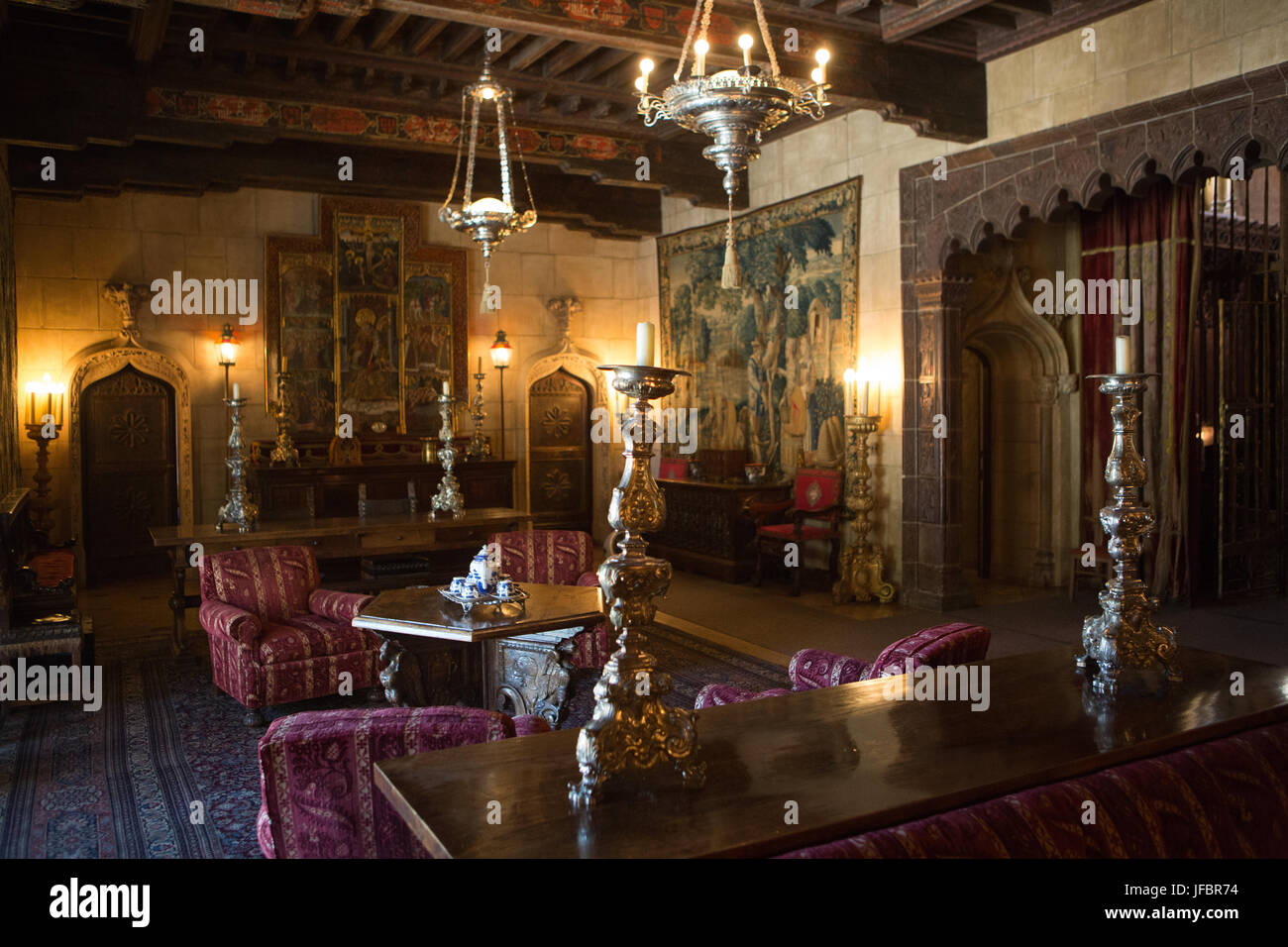 Il Castello di Hearst salotto arredato con mobili, arazzi, artwork, ceri ornati e punti luce. Foto Stock