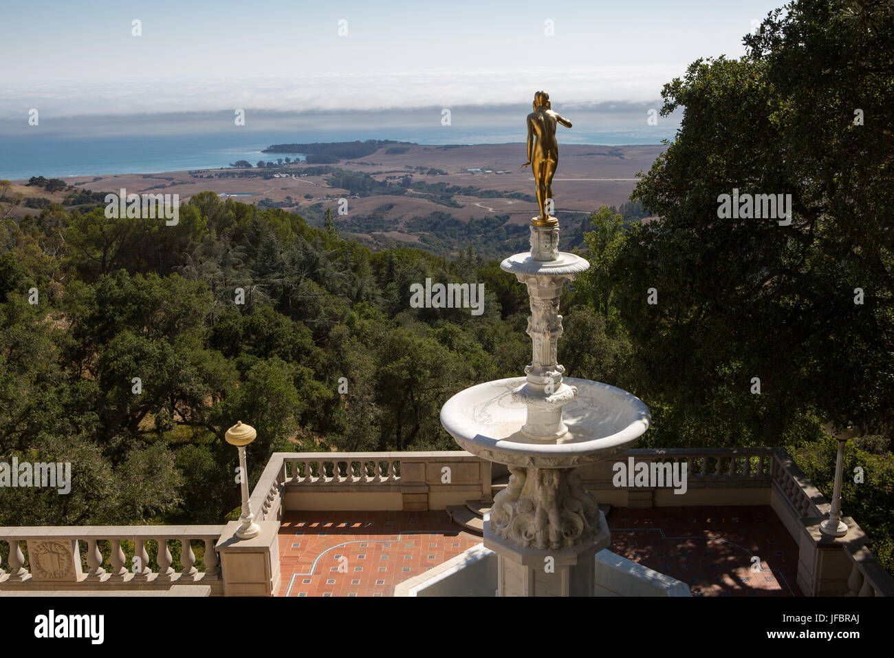 Una statua d'oro e una fontana su una veranda con vista sul Pacifico e la San Simeon costa. Foto Stock