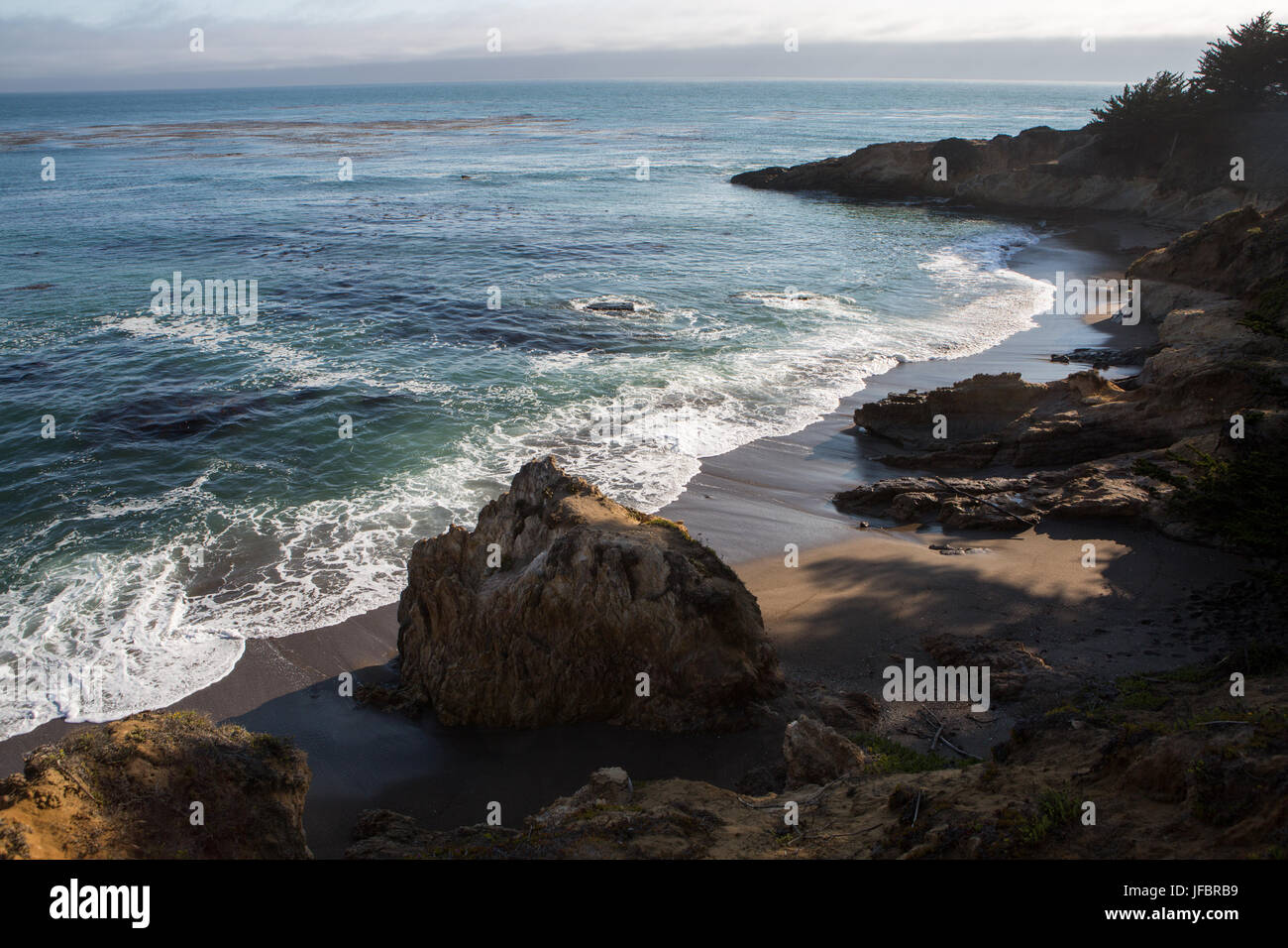 Onde venire a terra su una spiaggia con le formazioni rocciose a San Simeone Cove. Foto Stock
