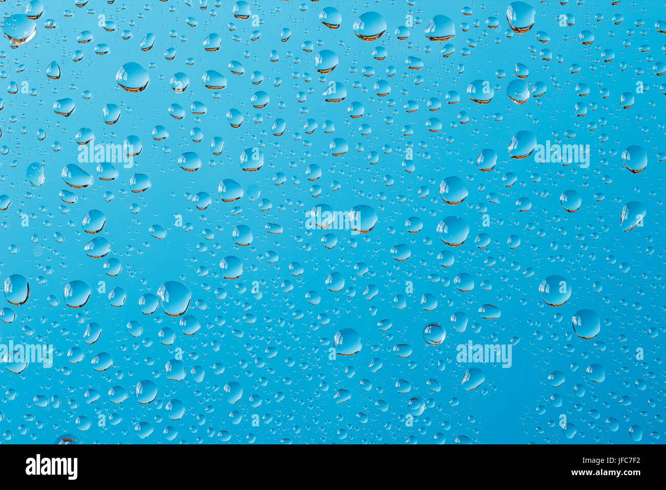 Macro shot di gocce di acqua su un vetro contro il turchese sfondo blu. Giorno di pioggia sfondo astratto Foto Stock