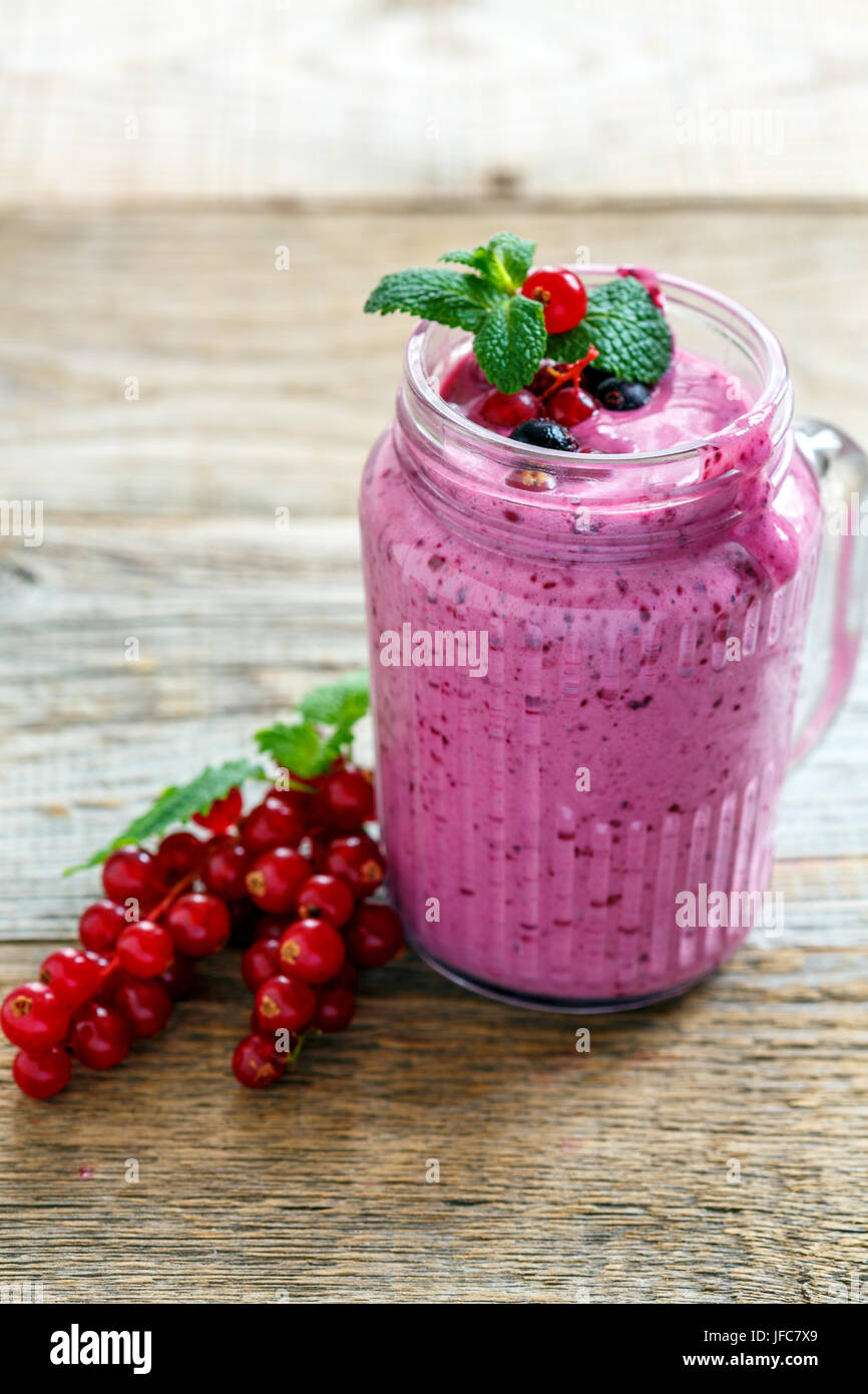 Vaso di vetro con berry smoothie e verde menta. Foto Stock
