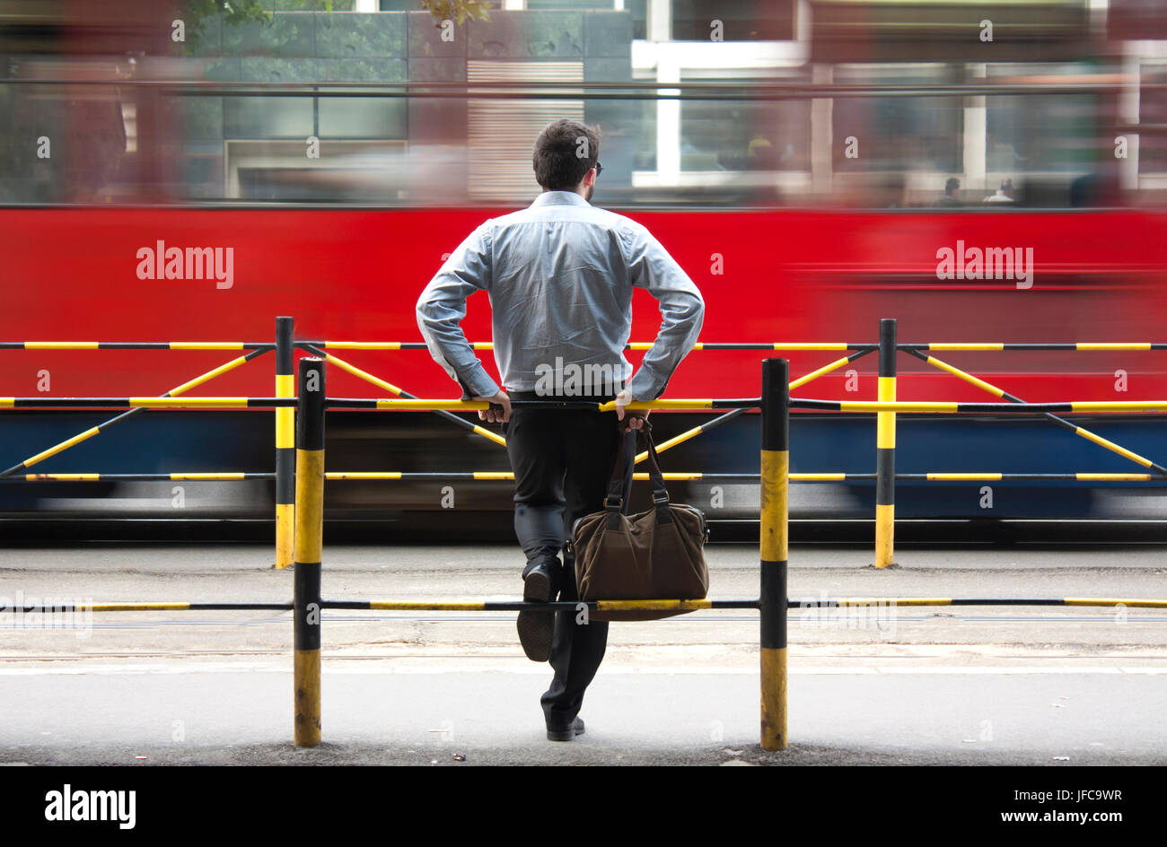Un giovane uomo di attesa per i mezzi di trasporto pubblico presso la fermata degli autobus Foto Stock