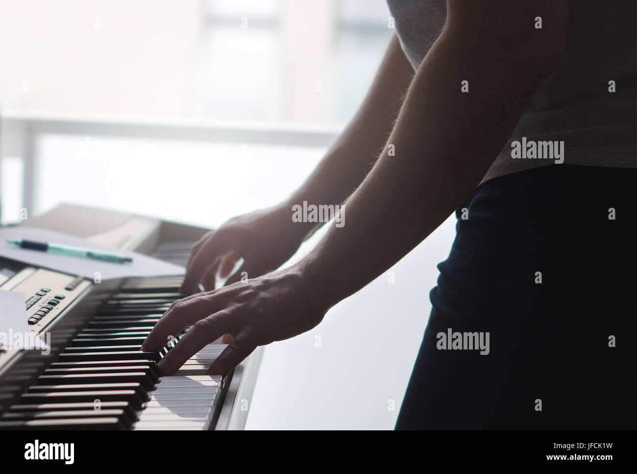 L'uomo suonare il pianoforte in piedi. Musicista di talento e il pianista pratica e abilità di treno dalla finestra. Nota carta e penna sullo strumento. Foto Stock