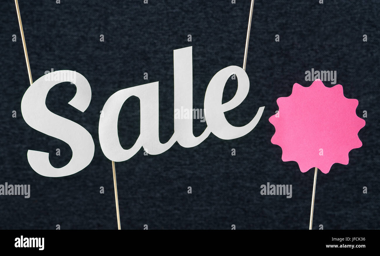Testo di vendita pendenti dal soffitto. Artigianato lettere taglio da cartone carta sul bastone di legno. Rosa cerchio rosso con libera copia vuota spazio per il testo. Foto Stock