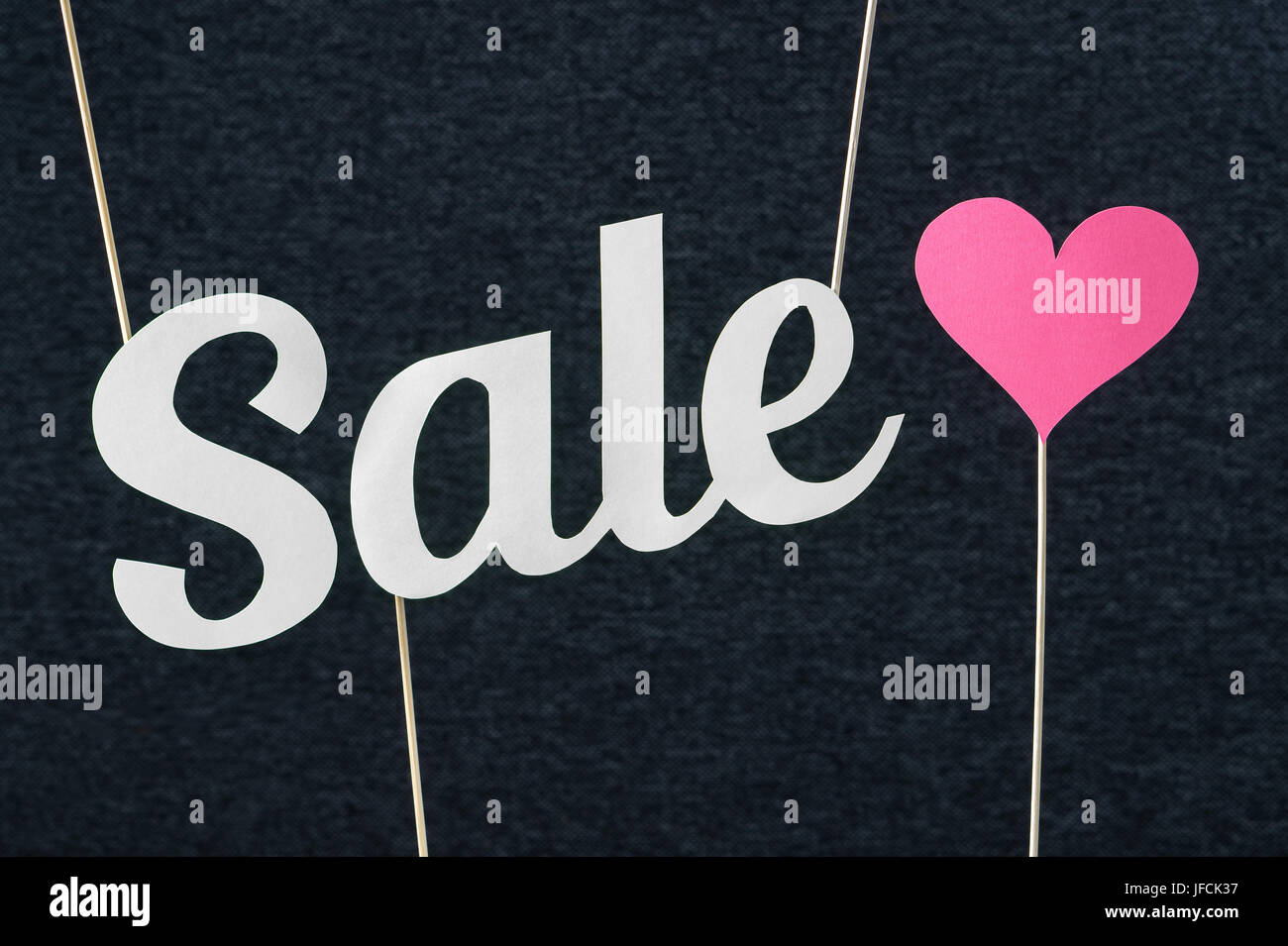 Vendita testo tagliato da cartone carta sul bastone di legno e uno sfondo scuro. Il materiale di marketing per San Valentino, donna o della mamma offerte speciali. Foto Stock