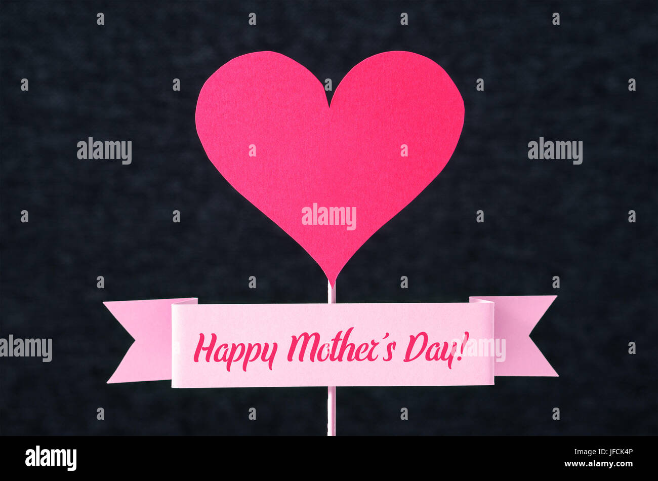 Felice Giorno della Madre il testo su un nastro e cuore rosso forma tagliata da un cartone sul bastone di legno. Bel Saluto semplice design per le madri Giorno della carta. Foto Stock