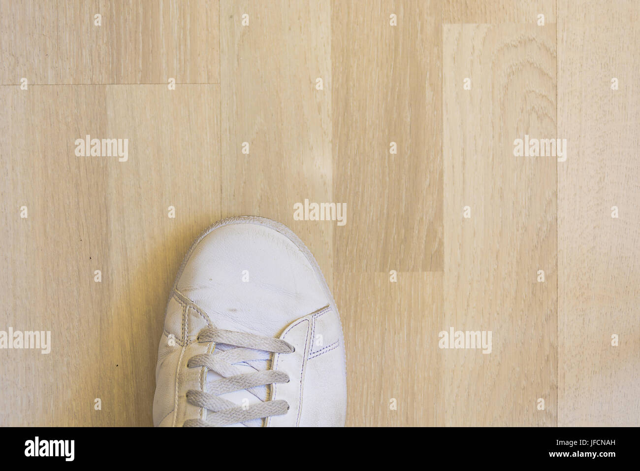 White sneaker scarpa sul pavimento in legno Foto Stock