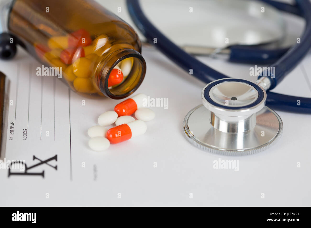 Medical stetoscopio in testa con un mucchio di compresse giacente sulla prescrizione closeup vuota. Sanitario, medico o il concetto di assicurazione Foto Stock