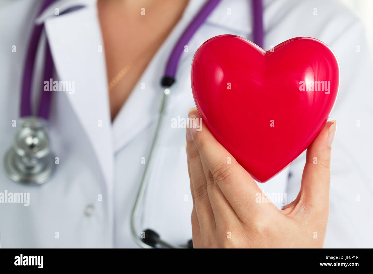 Medicina femminile medico tiene in mano il giocattolo rossa cuore closeup. Cardio terapeuta, medico rendere fisiche cardiache, frequenza cardiaca misurare o aritmia co Foto Stock