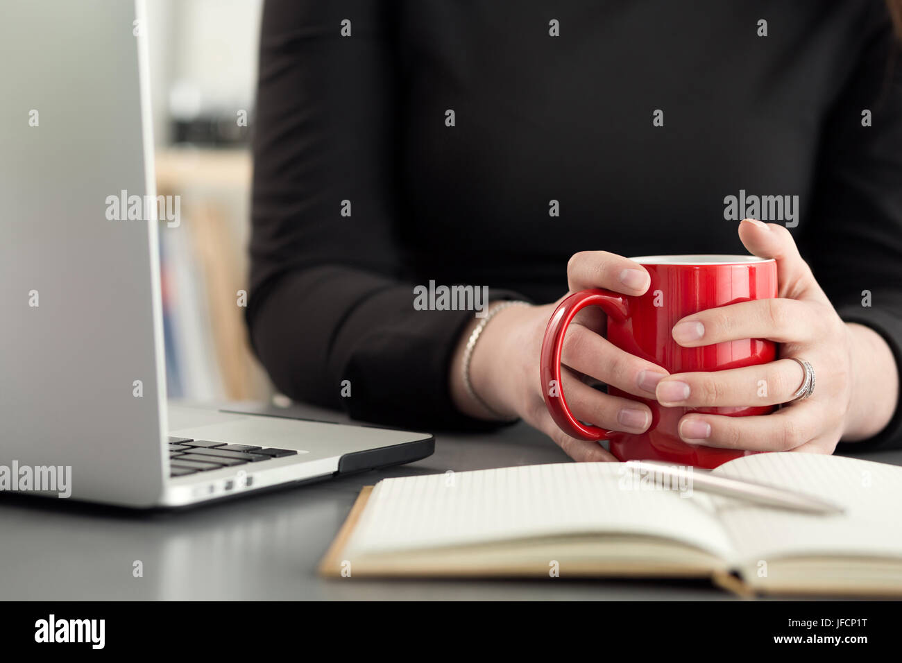 Designer femmina in ufficio al mattino bere il tè o il caffè. Coffeebreak durante la dura giornata lavorativa. Ragazza con tazza di bevanda calda. Foto Stock