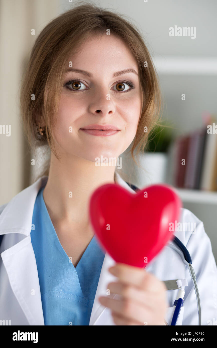 Medicina femminile medico tenere in mano giocattolo rossa cuore closeup. Cardio terapeuta, medico rendere fisiche cardiache, frequenza cardiaca misurare o aritmia con Foto Stock