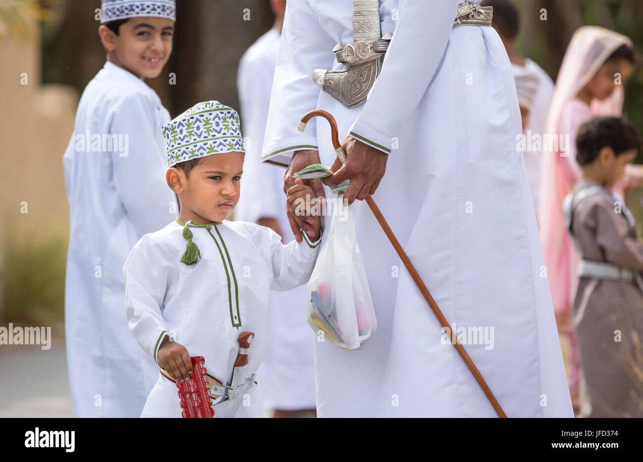 Nizwa, Oman - 26 Giugno 2017: famiglia in abbigliamento tradizionale a un giocattolo sul mercato un giorno di Eid Al Fitr, festa in occasione della fine del mese sacro del Ramadan Foto Stock