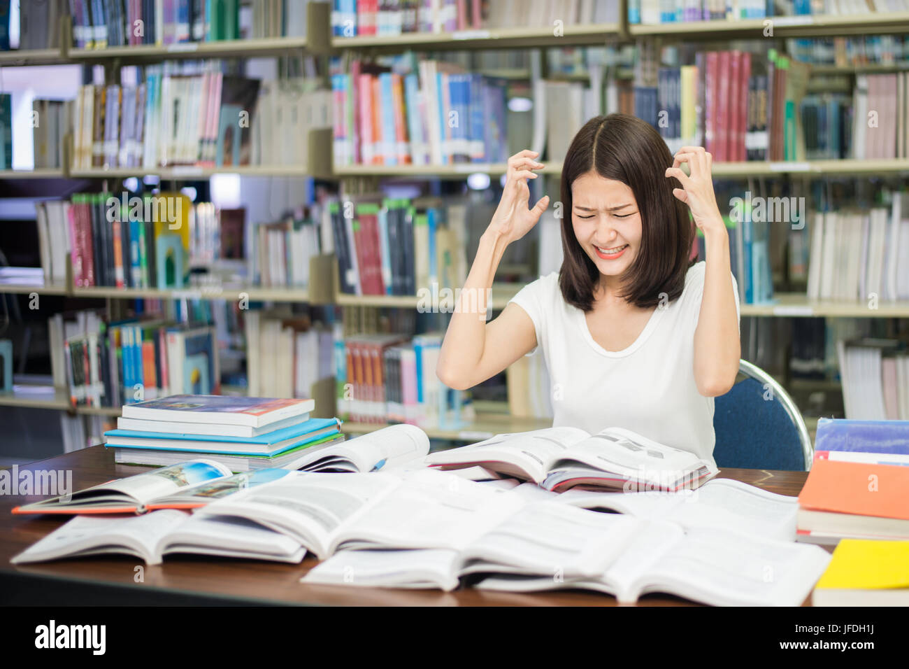 Giovani studenti asiatici sotto pressione mentale durante la lettura del libro preparazione esame nella biblioteca dell Università. Asian studente che sta cercando ha sottolineato. Foto Stock