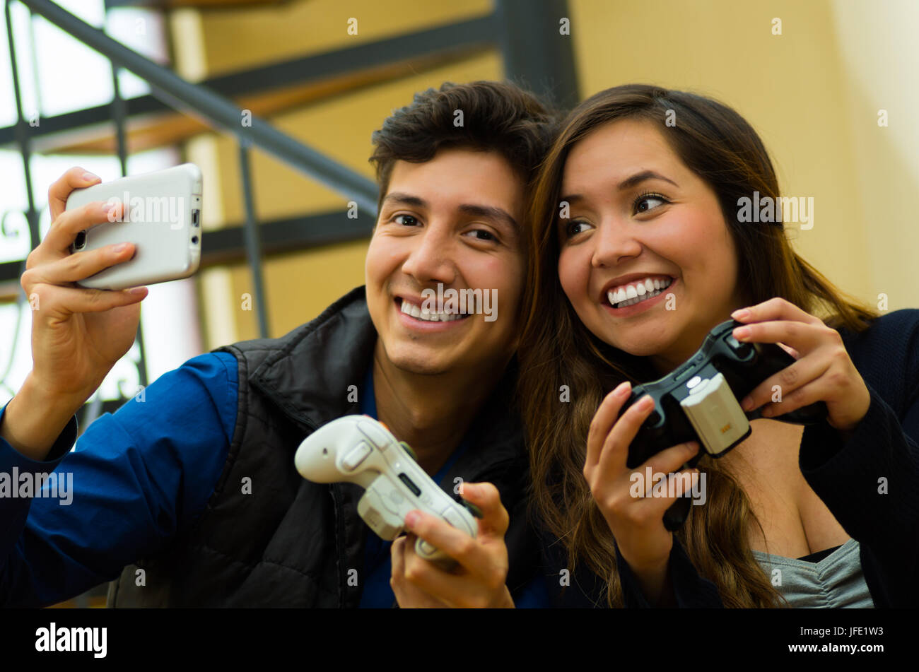 Bella giovane per giocare con i videogiochi sul lettino azienda nelle loro mani un gamepad mentre sta prendendo un selfie, il concetto di home entertainment, vide Foto Stock