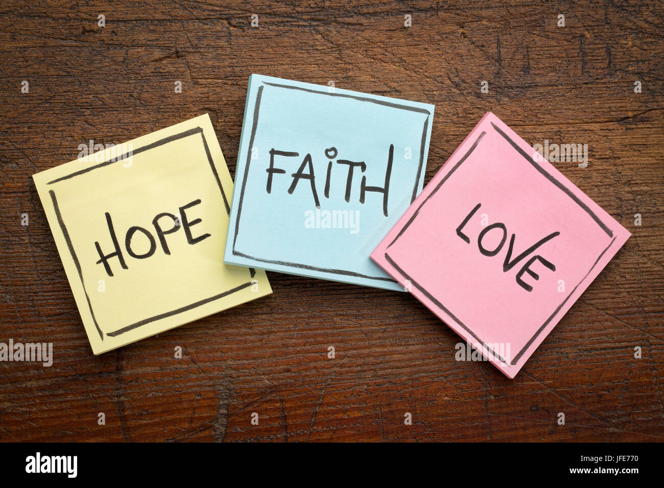 La fede, amore e speranza - colorata sticky notes su legno rustico Foto Stock