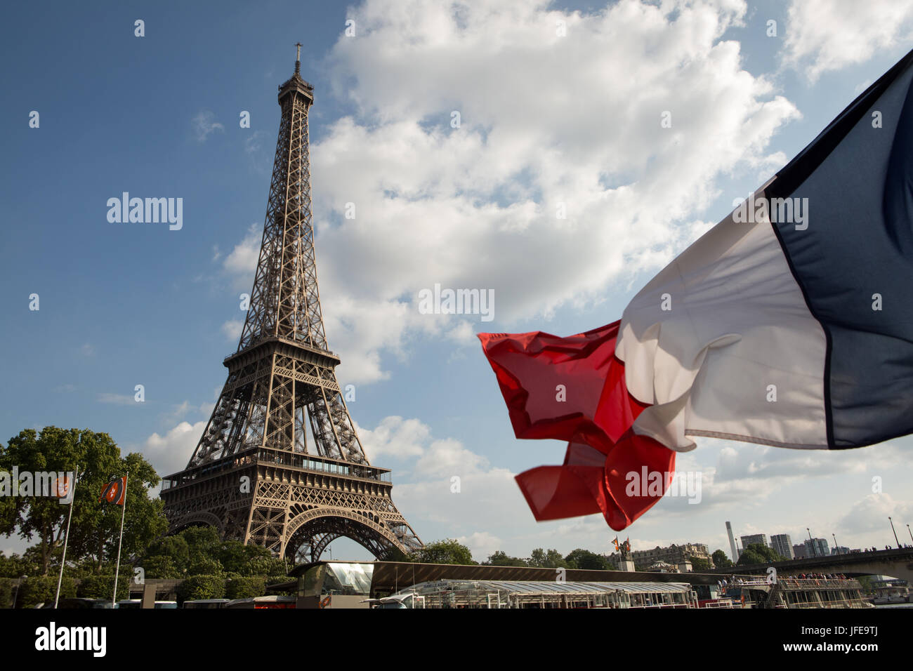 La bandiera francese soffia il vento di fronte alla Torre Eiffel. Foto Stock