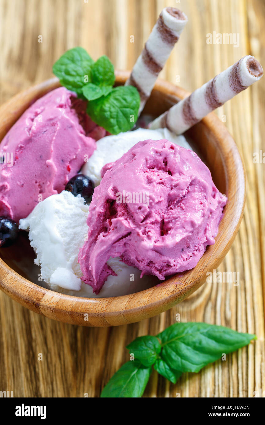Vanilno-berry gelato con rotoli di wafer in una ciotola di legno. Foto Stock