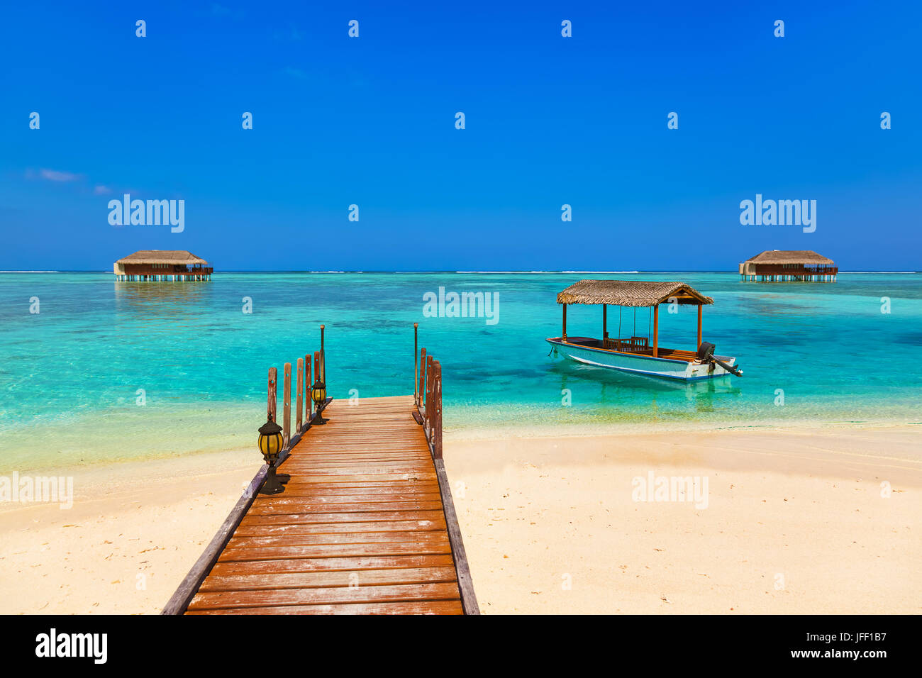 Barca e bungalow sull isola di Maldive Foto Stock