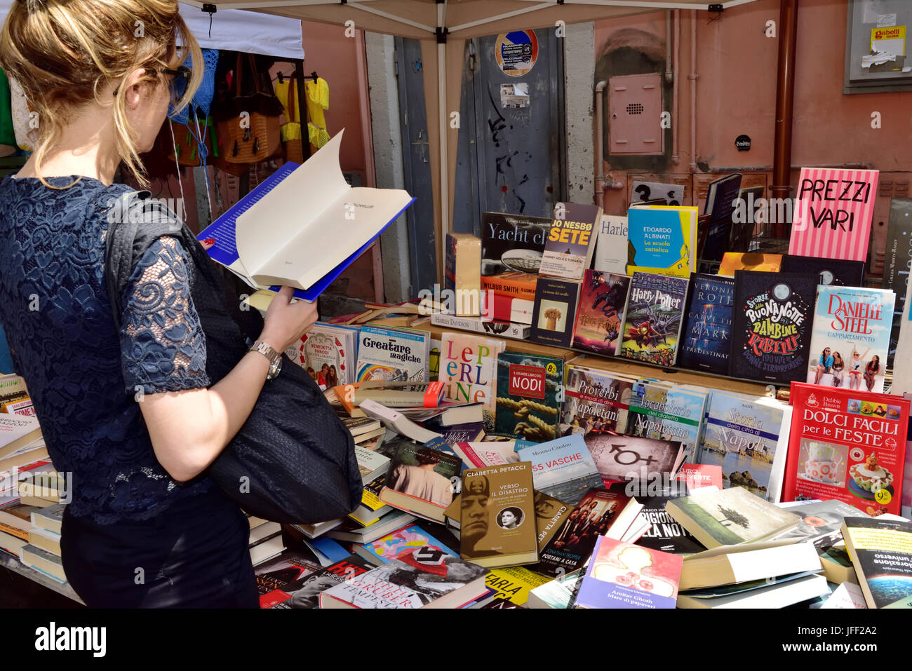 Donna esaminando un libro in stallo del mercato Foto Stock