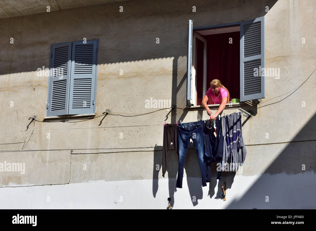 La donna nella finestra appeso il lavaggio, Italia Foto Stock
