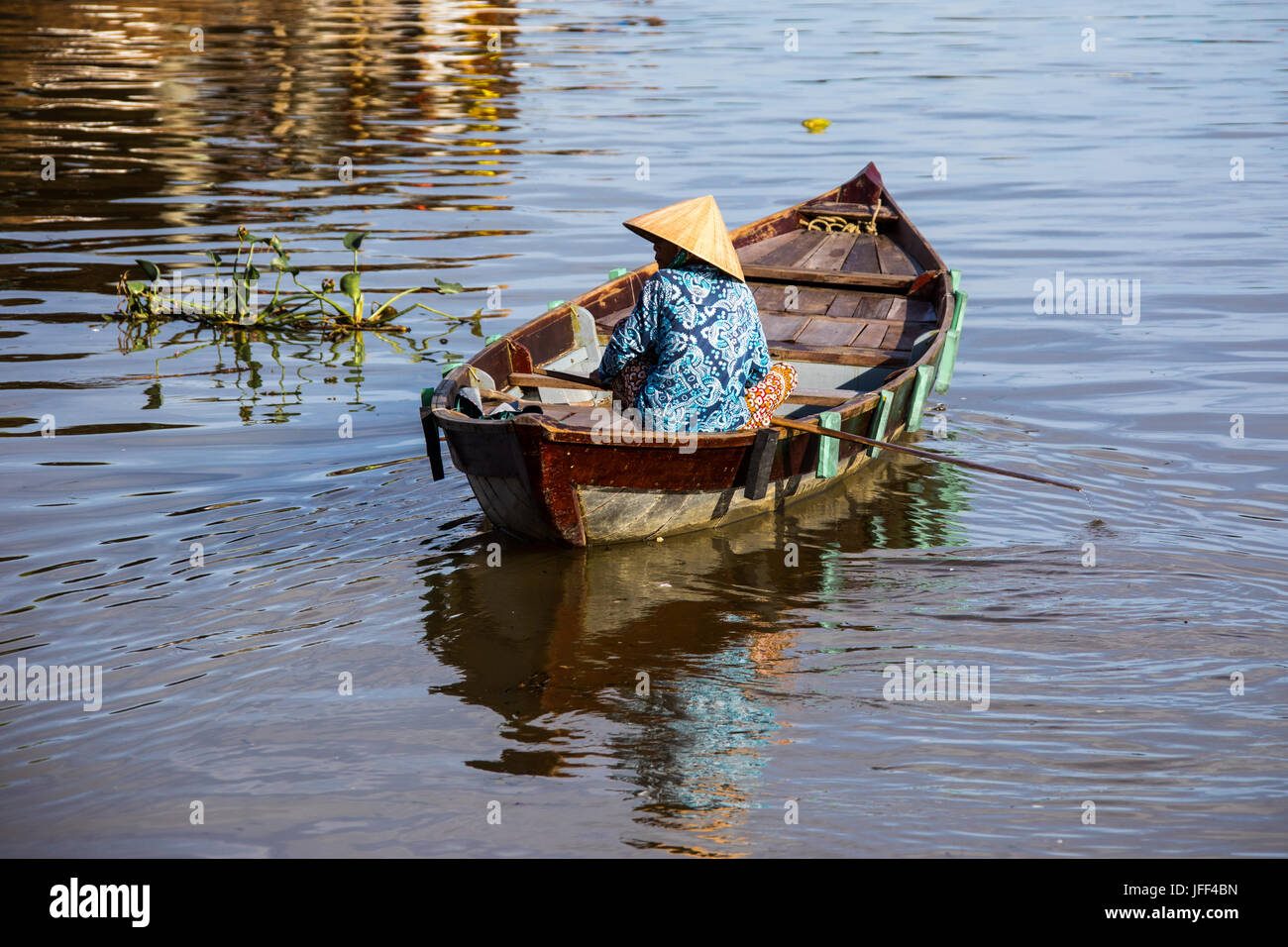 La donna in una barca a remi lookoing turistico per i clienti sul fiume Thu Bon in Hoi An, Vietnam Foto Stock