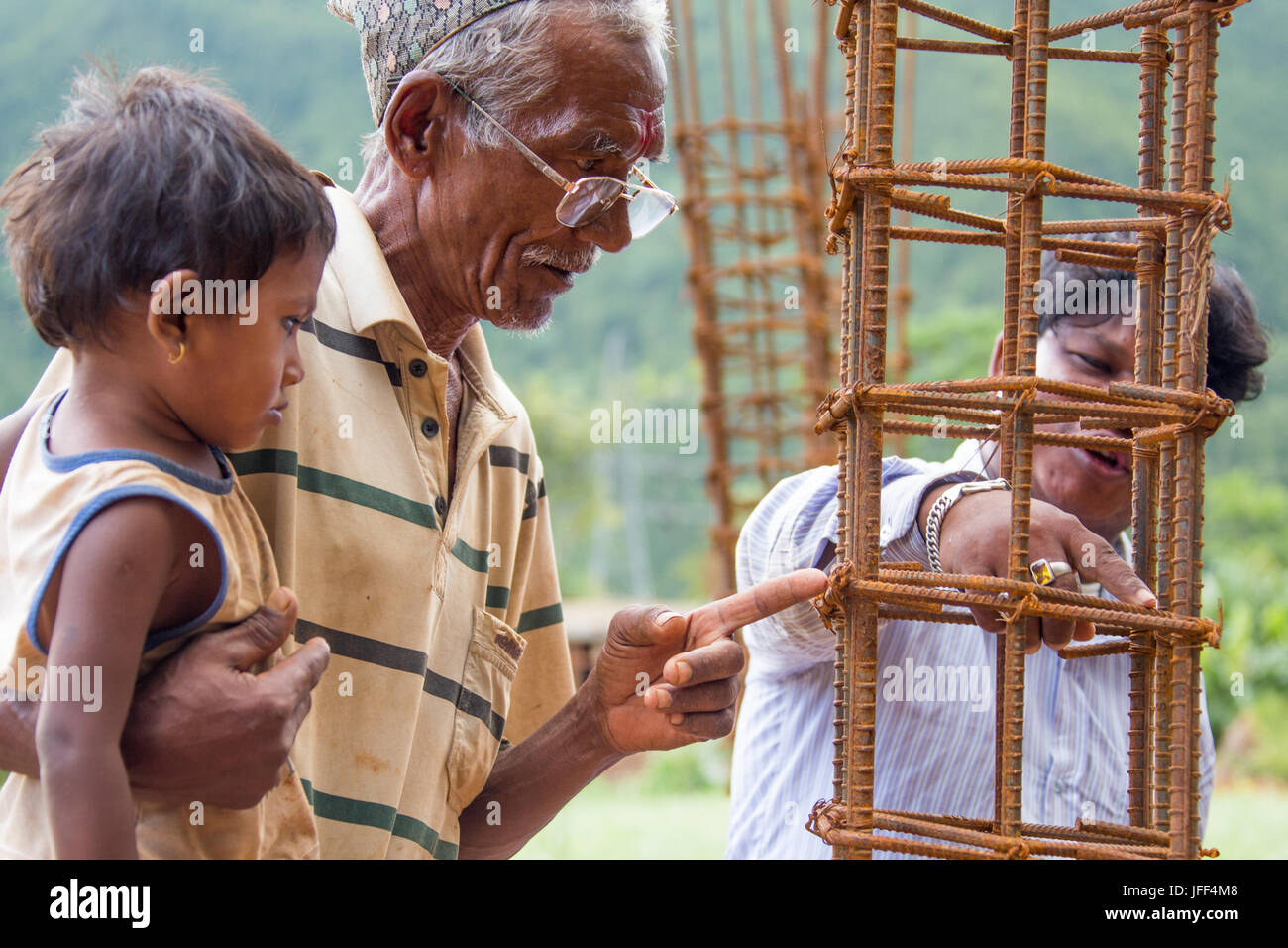 Mason (destra) spiegando terremoto resistent rebar tecniche che egli utilizzato per l'uomo (sinistra) Casa, Distretto di Nuwakot, Nepal Foto Stock