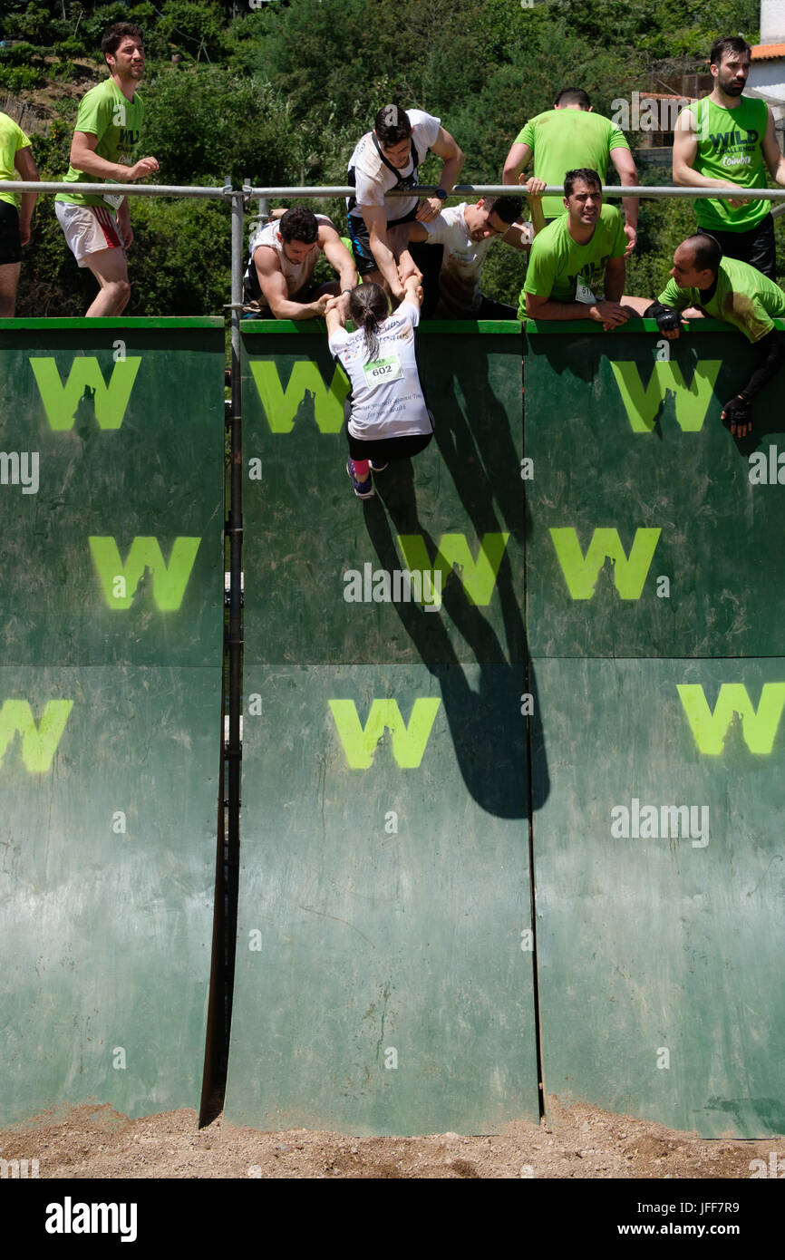 I concorrenti che si aiutano reciprocamente salire una parete durante una corsa a ostacoli gara Foto Stock
