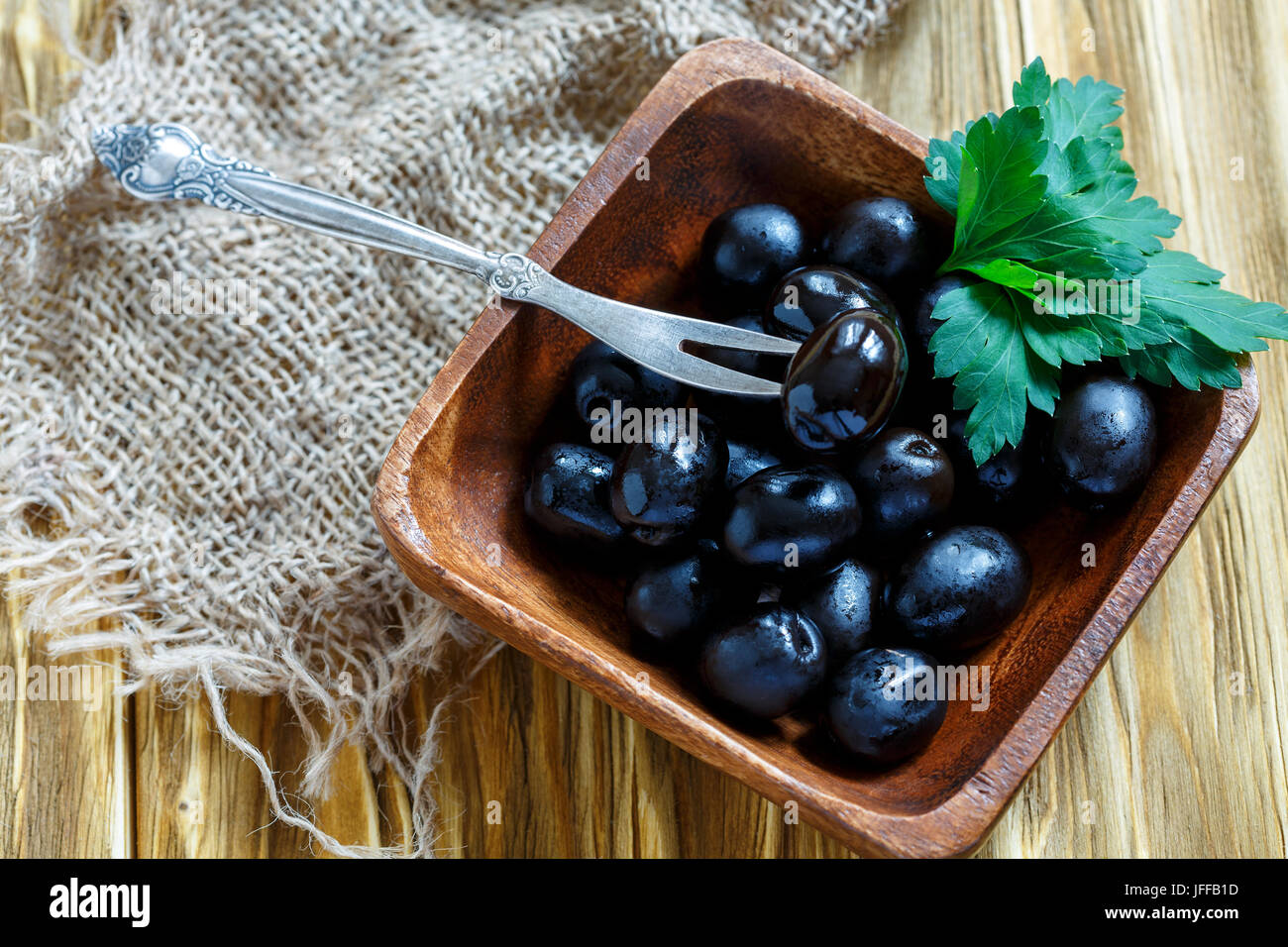 Forcella in una ciotola di legno con olive nere. Foto Stock