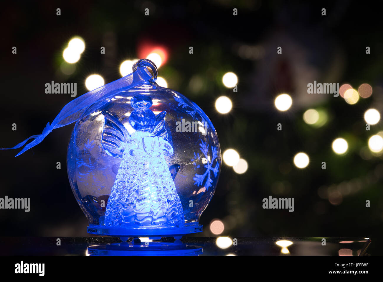 Illuminata figura di angelo in vetro della lampadina, soft bokeh di fondo le luci di Natale come sfondo, decorazione di Natale Foto Stock