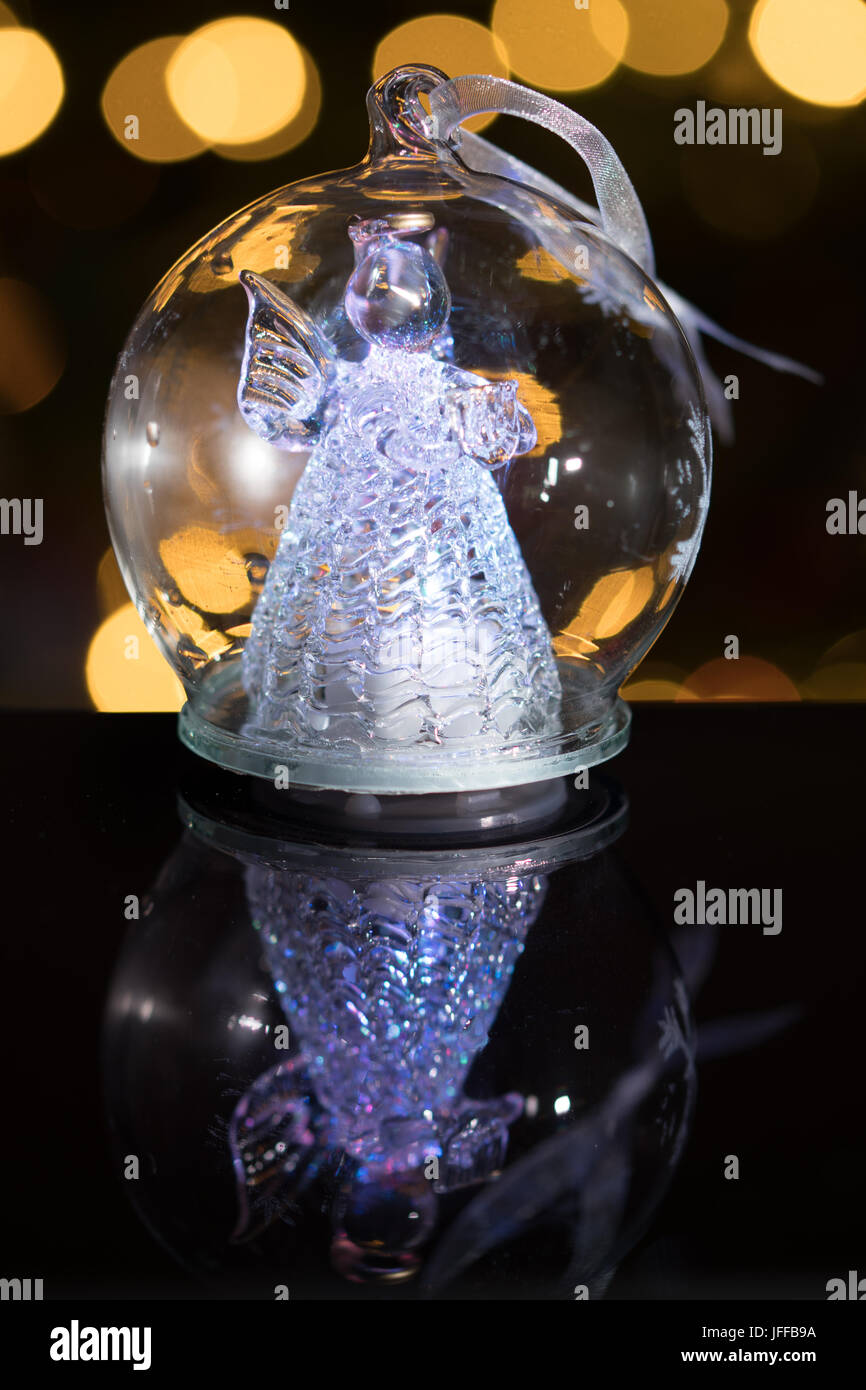 Illuminata figura di angelo in vetro della lampadina, soft bokeh di fondo le luci di Natale come sfondo, decorazione di Natale Foto Stock