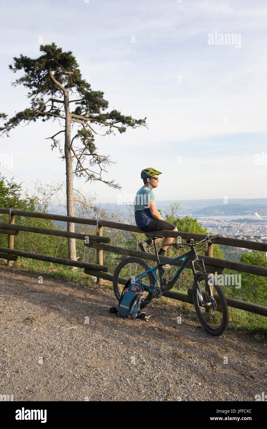 Mountain biker in appoggio mentre è seduto sulla ringhiera in legno Foto Stock