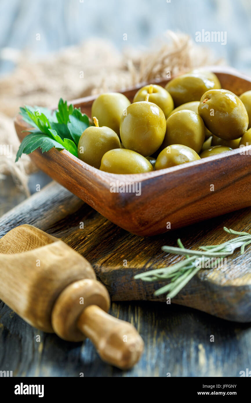 Ciotola con olive verdi e un cucchiaio di legno. Foto Stock