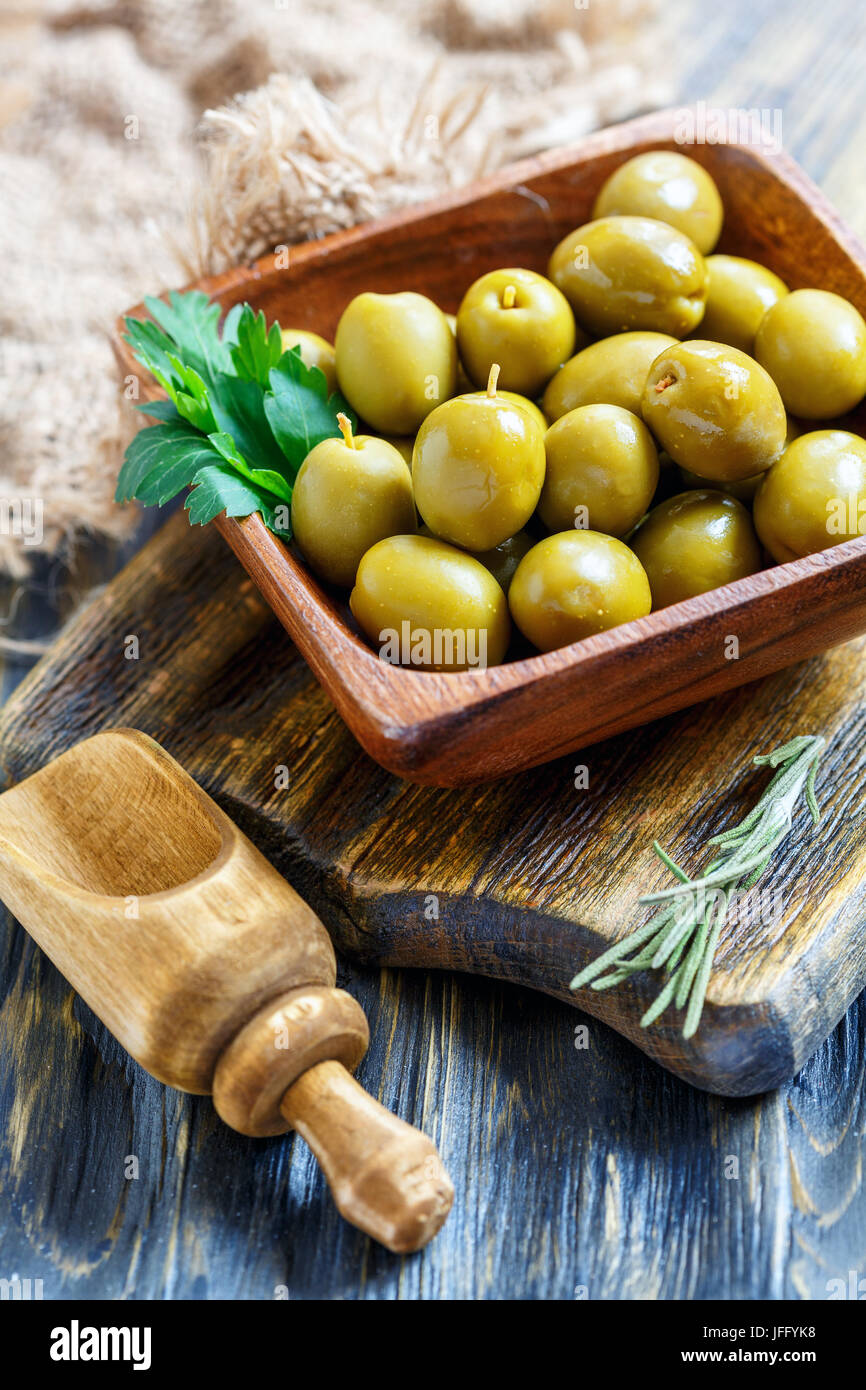 Olive verdi in una ciotola e un rametto di prezzemolo. Foto Stock