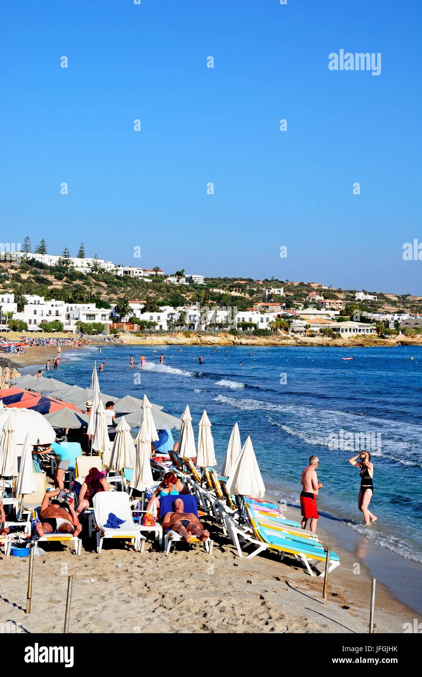 I turisti rilassante sulla spiaggia con vista lungo la costa, Hersonissos Creta, Grecia, l'Europa. Foto Stock