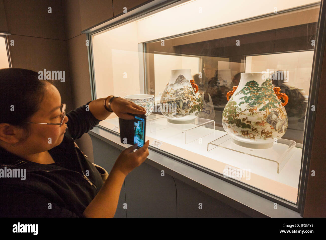 Cina, Shanghai, il Museo di Shanghai, ragazza prendendo foto di antiche ceramiche Display Foto Stock