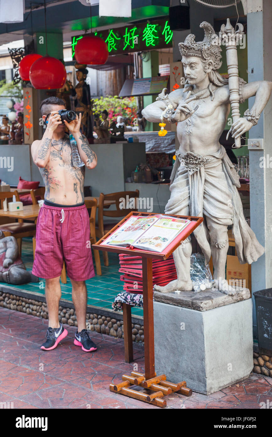 Thailandia, Bangkok, Khaosan Road, giovane viaggiatore straniero tenendo la foto della statua Foto Stock