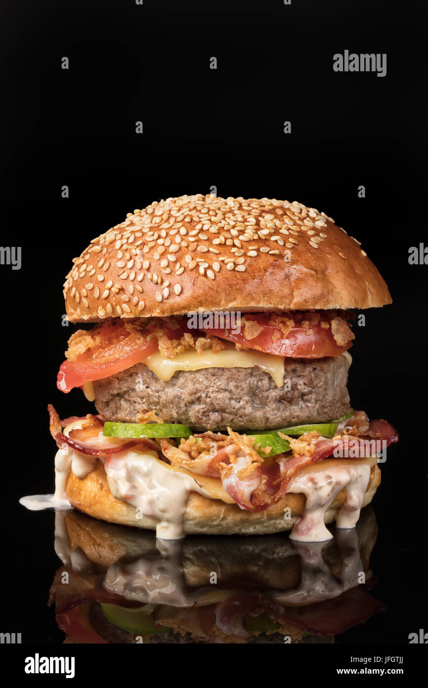 Burger con manzo e verdure su un vetro riflettente sullo sfondo Foto Stock