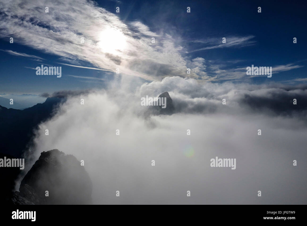 Rock summit sorge offuscata dal mare di nuvole, Oberreintalschrofen, vista del Schüsselkarspitze, gamma Wetterstein Foto Stock