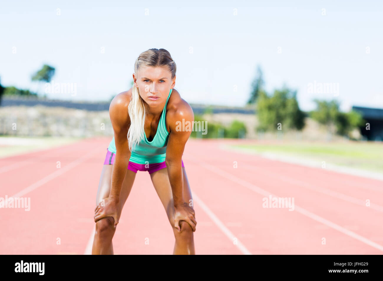 Stanco atleta femminile permanente sulla via di corsa Foto Stock