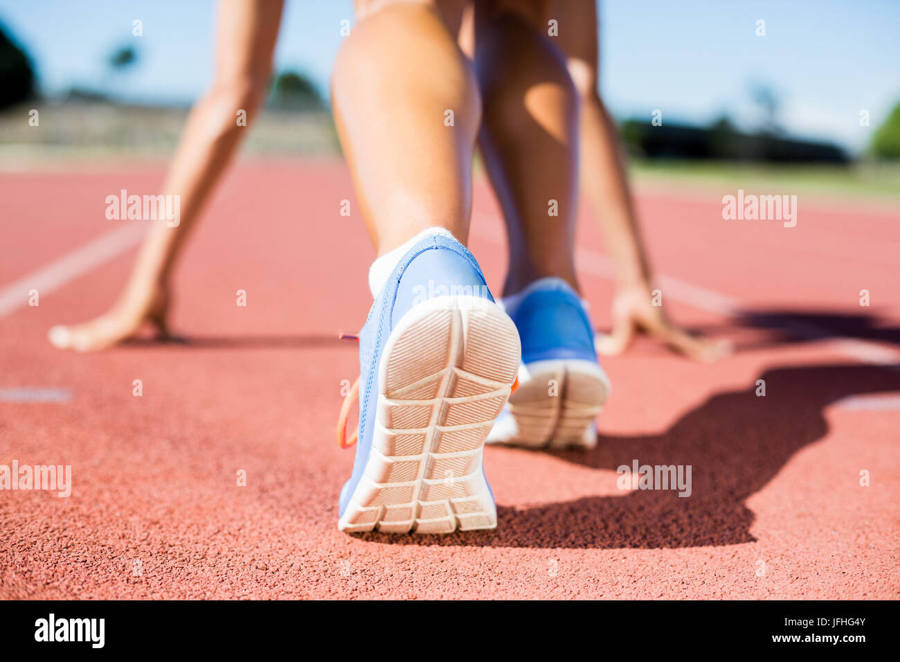 Atleta femminile pronto a correre su una pista per la corsa Foto Stock